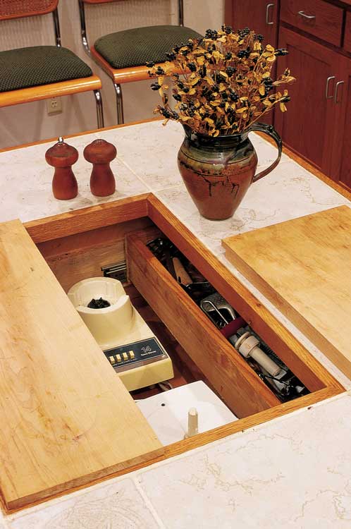 Joy’s storage unit in the recessed center of her kitchen island includes electrical outlets, so she can just pop up the blender or the food processor. Thin spaces flanking the built-in bookshelf were put to use for key and skewer storage.